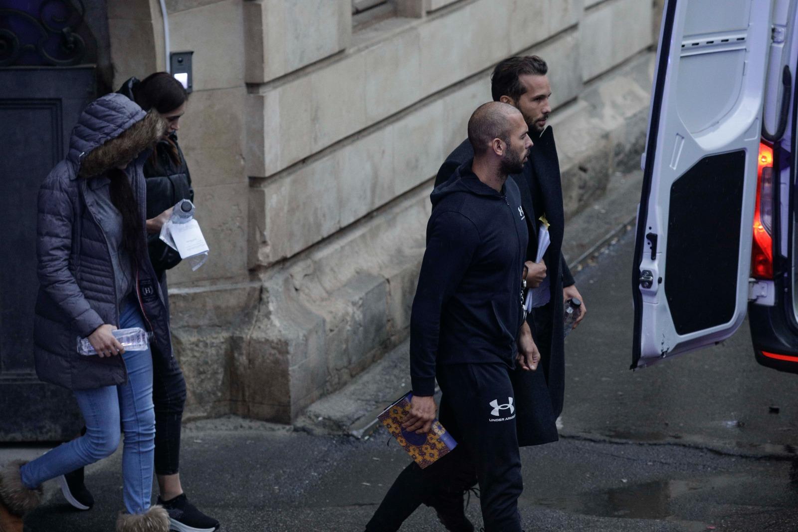 Fraţii Tate, legaţi amândoi cu o pereche de cătuşe, au stat 5 ore la tribunal. Mesajul afişat de un susţinător