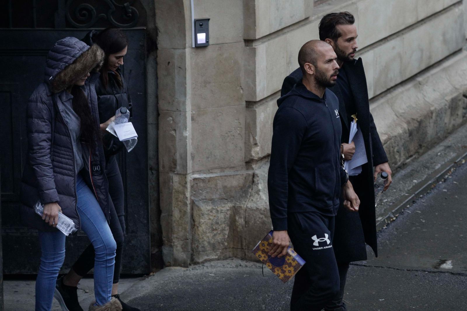 Fraţii Tate, legaţi amândoi cu o pereche de cătuşe, au stat 5 ore la tribunal. Mesajul afişat de un susţinător