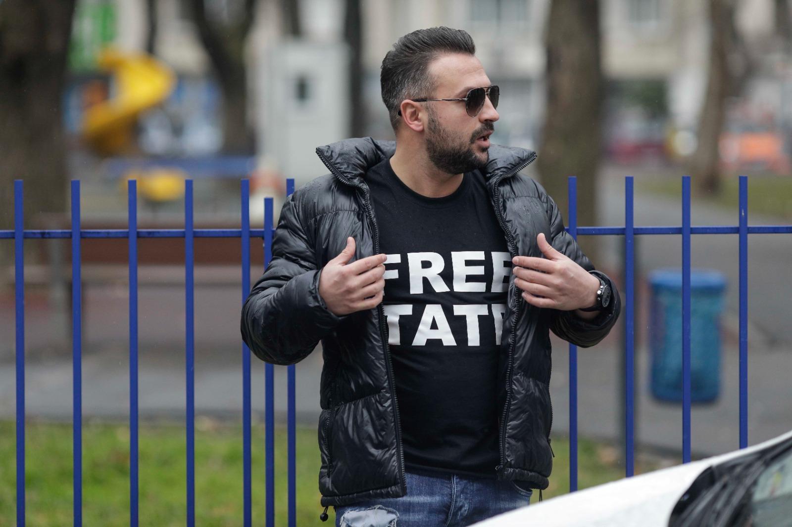 Fraţii Tate, legaţi amândoi cu o pereche de cătuşe, au stat 5 ore la tribunal. Mesajul afişat de un susţinător