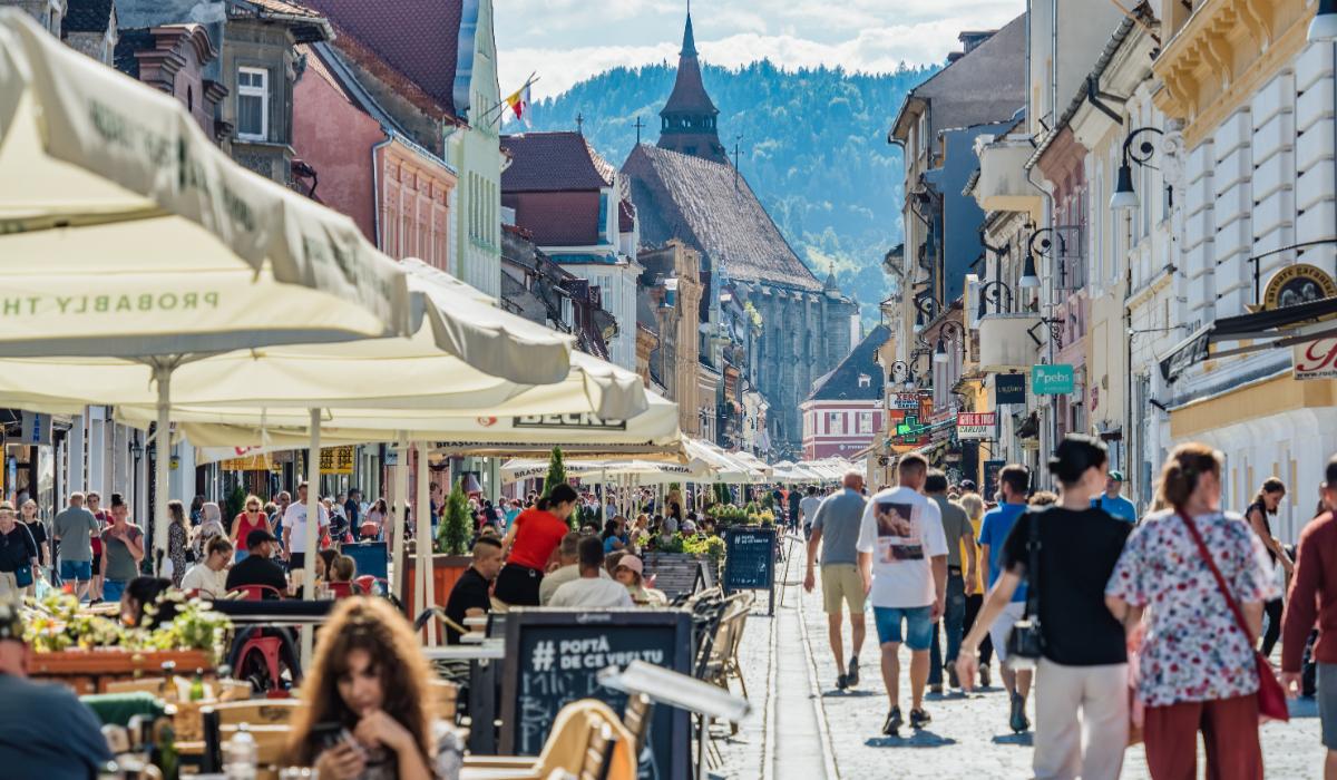 Turiști și localnici se plimbă pe zona pietonală din centrul vechi al Brașovului.