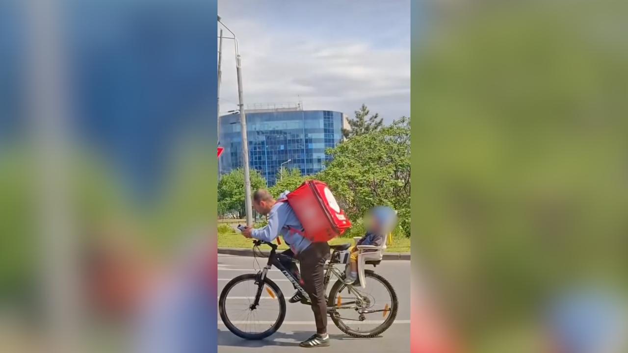 Imagine emoţionantă în Bucureşti: Un livrator surprins cu copilul pe bicicletă, în timp ce îşi ducea comenzile. Micuţul adormise în scaunul său