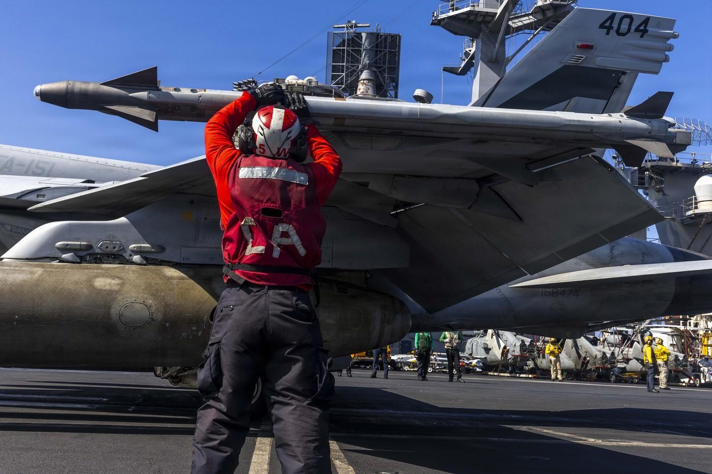 Militar american care înarmează un avion de vânătoare F/A-18E Super Hornet, pe un portavion