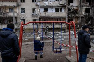 Copiii care se dau în leagăn în fața blocului distrus de bombardamente, în Kiev. GALERIE FOTO