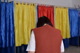 Femeie introduce buletinul de vot în urnă