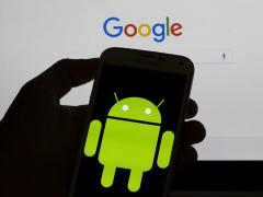 Logo-ul Android afişat pe un smartphone, în faţa unui monitor cu Google Search