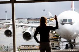 Femeie care priveşte avionul tras la terminalul aeroportului