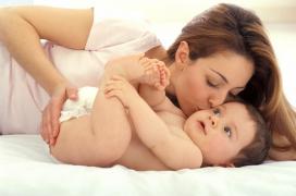O mămică aflată în concediu maternal îşi sărută bebeluşul