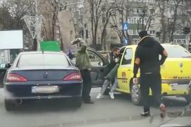 Video cu bătaie în trafic în București! Un taximetrist e tras de picioare din mașină și lovit cu pantoful de doi bărbați
