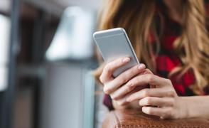 Tânără ține telefonul în mână