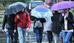 Oameni în ploaie pe o stradă din București