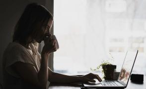 Tânără se uită pe Internet la laptop