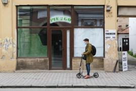 Un bărbat pe trotinetă trece pe lângă un spațiu comercial închis din cauza restricțiilor pentru limitarea răspândirii Covid-19, în Cluj