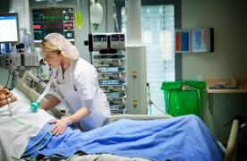 O asistentă oferă îngrijiri unui bătrân aflat la Terapie Intensivă