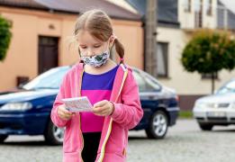 Fetiţă îmbrăcată predominant în roz care ţine în mână un bilet