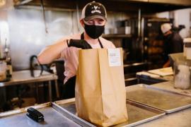Un angajat al unui restaurant pregătește un pachet cu mâncare pentru livrare