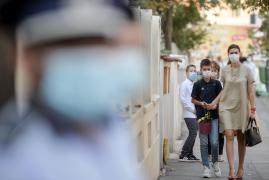 O mamă își însoțește copilul la școală, purtând mască de protecție