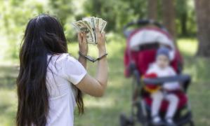 Bebeluş în cărucior în drpetul unei femei cu cătuşe care ţine în mână bani