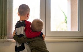 Doi băieţi îmbrăţişaţi, privind la geam