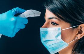 Femeie cu mască de protecţie testată pentru temperatură