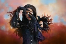 O femeie frumoasă îmbrăcată în stil gotic ține un glob de cristal în mâini