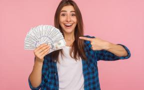 Tânără care tine în mână un teanc de bani şi zâmbeşte