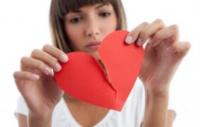 Tânără care rupe o inimă roşie din hârtie