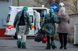 O femeie este condusă de medici la ambulanţă