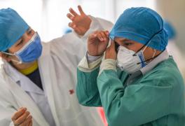 Doi medici se îmbracă cu costume de protecţie