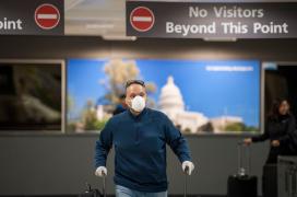 Un pasager cu mască și mănuși în aeroport