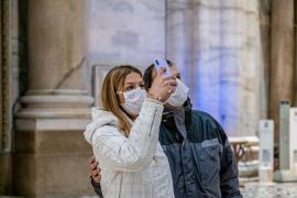 Doi turişti fac poze cu măştile pe faţă