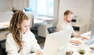 Femeie care lcurează la un calculator, în birou