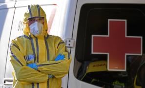 Medic cu costum de protecție contra coronavirus, lângă o ambulanță