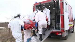 Medici în costum de protecţie preiau cu izoleta un bolnav de coronavirus