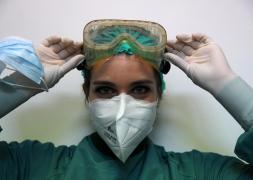 Asistentă medicală cu mască sanitară își pune ochelarii