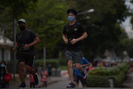 Tineri care aleargă cu mască de protecție pe față