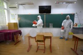 Bărbaţi în combinezoane dezinfectează o clasă
