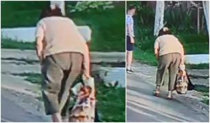 Femeia de 70 de ani apare filmată doar din spate, cu o pungă în mână, și se deplasează greoi, aplecat.