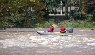 Imagine reprezentativă cu o echipă de salvatori căutând cu barca pe râu