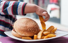 Copil supraponderal mâncând cartofi prăjiţi