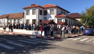 Oameni care așteaptă la coadă în fața unei secții de votare