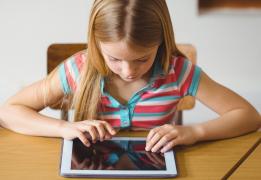 O fetiţă scrie la o tabletă