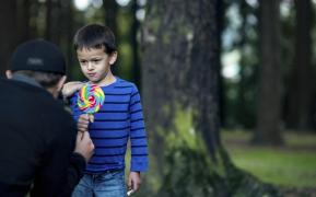 Copil ademenit cu o bomboană de un bărbat care stă cu spatele