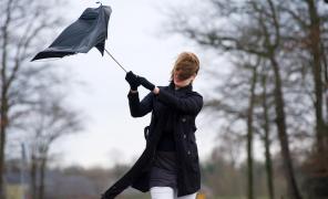 Femeie ţine în mână umbrela ruptă de vânt