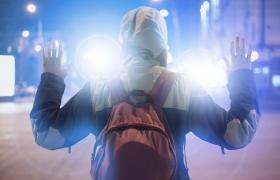 Copil cu mâinile ridicate în faţa unei maşini cu farurile aprinse