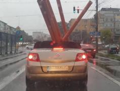 Imagini virale. Craiovean, filmat în timp ce transporta cu un Renault Megane decapotabil mai multe țevi, pe ploaie