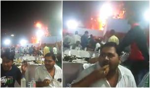 Doi invitați la o nuntă din India rămân la masă și continuă să mănânce liniștiți, în timp ce un foc uriaș arde tot în spatele lor