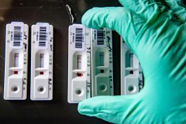 Un asistent așează mai multe teste rapide Covid-19 pe o masă