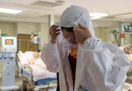 O asistenta medicală își aranjează costumul de protecție, într-o secție Covid