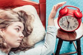 O tânără se trezește și oprește ceasul deșteptător dimineața