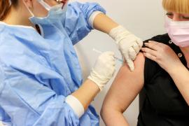 O femeie este vaccinată cu AstraZeneca, de către un lucrător medical, la un centru de vaccinare